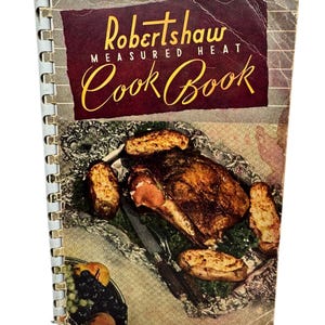 May include: A vintage Robertshaw Measured Heat Cookbook with a spiral binding. The cover features a photo of a roasted meat with potatoes on a silver platter.