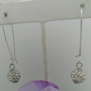 May include: A pair of silver dangle earrings with a round, clear crystal ball at the end of each earring.