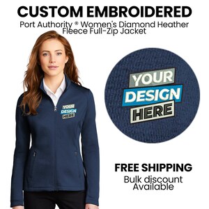 May include: A navy blue fleece full-zip jacket with a zipper closure and two front pockets. The jacket has a mock neck and is embroidered with the text "YOUR DESIGN HERE".