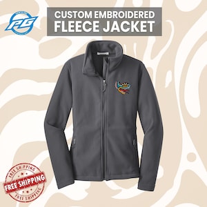 May include: A charcoal gray fleece jacket with a full zipper and a stand-up collar. The jacket features a colorful embroidered design on the upper left chest and the text "CUSTOM EMBROIDERED FLEECE JACKET" at the top.