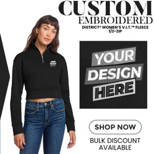May include: Black embroidered fleece with a 1/2-zip, featuring the text "YOUR DESIGN HERE." The image also includes the text "CUSTOM EMBROIDERED" and "SHOP NOW." The model is wearing blue jeans.