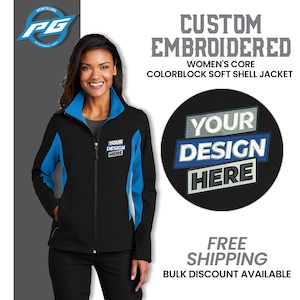 May include: A black, blue, and white colorblock soft shell jacket with a zipper closure. The jacket has a mock neck and two front pockets. The text "YOUR DESIGN HERE" is embroidered on the jacket.