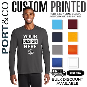 May include: A dark gray long-sleeve performance blend tee with the text "YOUR DESIGN HERE" in white. The image includes color swatches and the text "CUSTOM PRINTED", "PORT & CO" and "BULK DISCOUNT AVAILABLE".