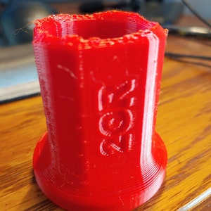 Può includere: Un oggetto rosso stampato in 3D con la parola "Zort" stampata sul lato.