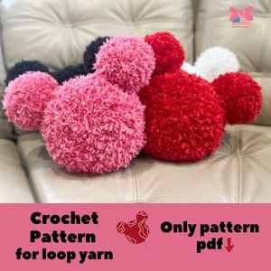 May include: Three crocheted Mickey Mouse head pillows in pink, red, and white. The pillows are made with fluffy loop yarn and are sitting on a light brown couch. The text "Crochet Pattern for loop yarn" and "Only pattern pdf" is visible at the bottom of the image.