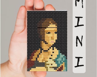 May include: A small, colorful pixel art portrait of a woman with a gold headband, wearing a blue and gold patterned dress. The art is framed and held in a hand.