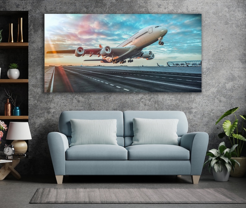 May include: A white airplane taking off from a runway with a blue sky and clouds in the background.