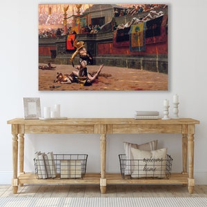 May include: A large canvas print of a historical painting depicting a Roman gladiator scene. The artwork shows a gladiator in golden armor standing over a fallen opponent in an arena, with a crowd in the background. The color palette is dominated by warm tones.