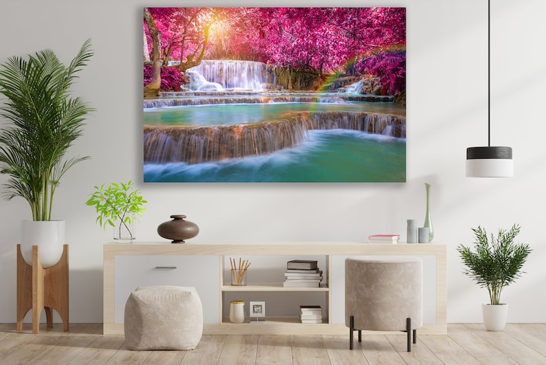 May include: A vibrant landscape painting featuring a cascading waterfall surrounded by lush greenery and pink trees. The water is clear and turquoise, and the trees are in full bloom.