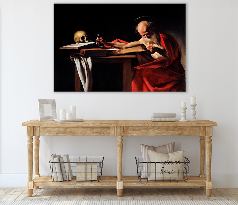 May include: A painting of a man with a long white beard sitting at a table and writing in a book. He is wearing a red robe and a halo. A skull is on the table next to him.