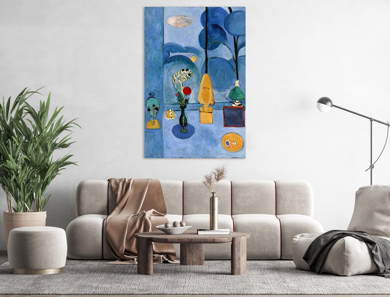 May include: A large, framed abstract painting with a blue and yellow color palette. The artwork features stylized shapes, including trees, vases, and a sun-like circle. The painting is displayed above a beige sofa in a living room setting.