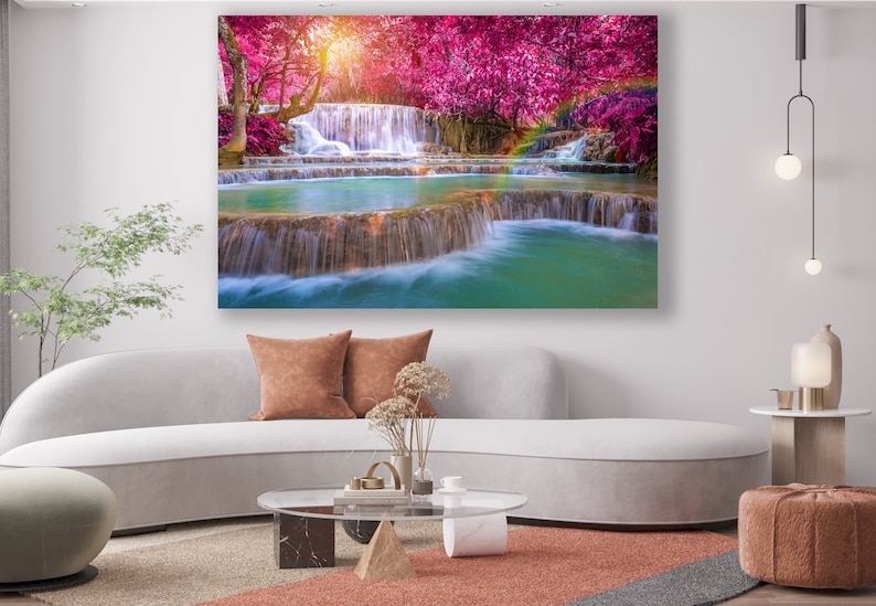 May include: A scenic photograph of a waterfall cascading through a lush forest with vibrant pink trees. The water is clear and turquoise, and the surrounding foliage is green and lush.