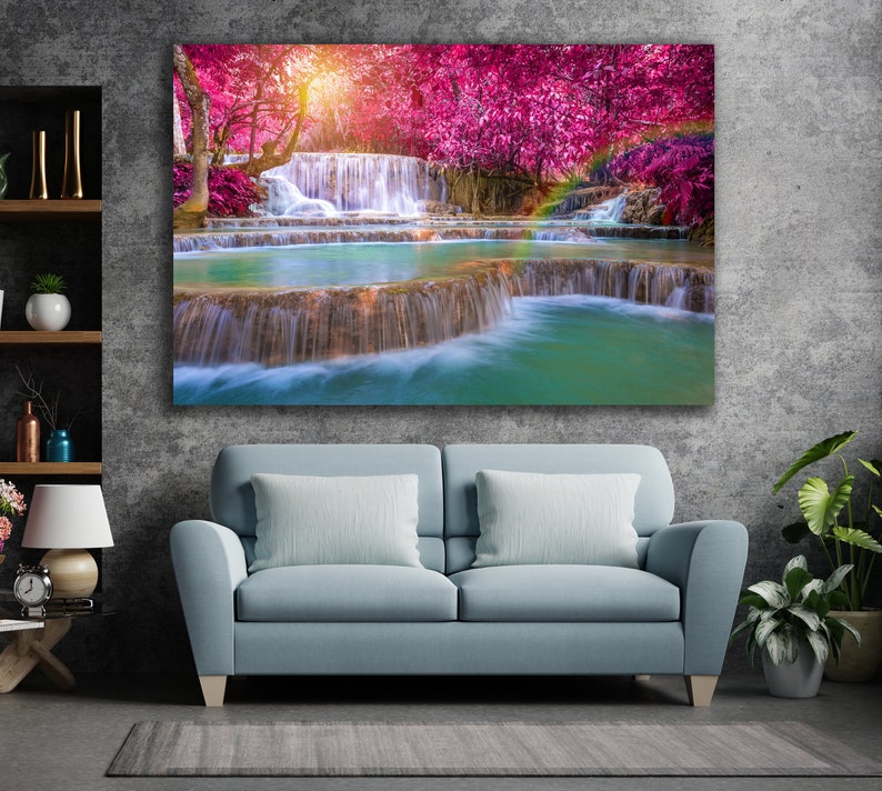 May include: A vibrant landscape painting featuring a cascading waterfall surrounded by lush greenery and pink flowering trees. The water flows over rocks and creates a tranquil scene.