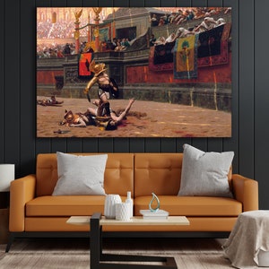 May include: A large framed canvas print depicting a historical scene of gladiators in an arena. The artwork shows a gladiator standing over a fallen opponent, with spectators in the background. The color palette includes browns, reds, and golds, creating a dramatic and historical ambiance.