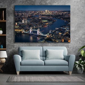 May include: An aerial view of the Tower Bridge in London at night. The bridge is lit up and the city lights are visible in the background.