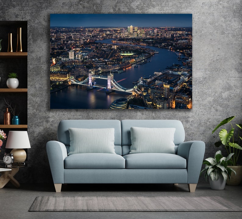 May include: An aerial view of the Tower Bridge in London at night. The bridge is lit up and the city lights are visible in the background.