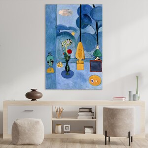 May include: Abstract art print featuring a blue and yellow color palette. The artwork depicts stylized shapes, including a vase of flowers, a yellow form, and a circular object. The painting is displayed on a white wall above a wooden cabinet.