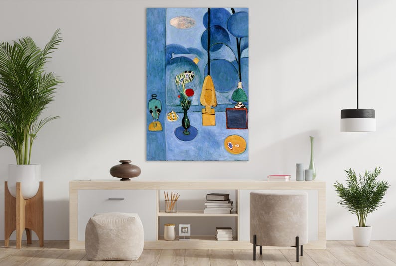 May include: Abstract art print featuring a blue and yellow color palette. The artwork depicts stylized shapes, including a vase of flowers, a yellow form, and a circular object. The painting is displayed on a white wall above a wooden cabinet.