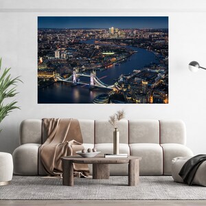 May include: An aerial view of the Tower Bridge in London at night. The bridge is lit up and the city lights are visible in the background.
