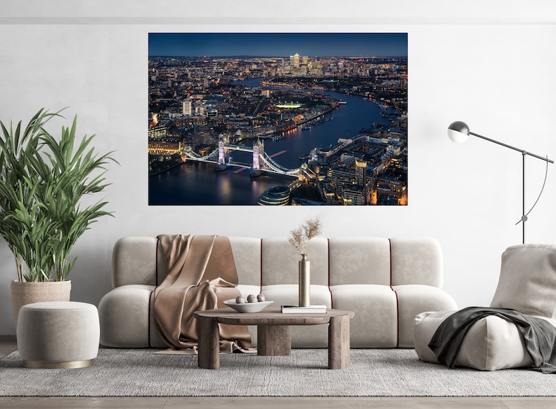 May include: An aerial view of the Tower Bridge in London at night. The bridge is lit up and the city lights are visible in the background.