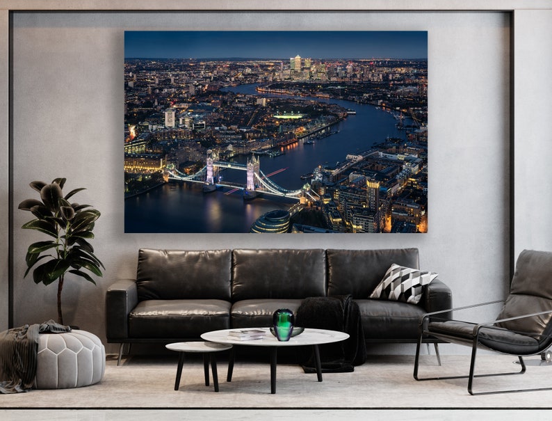 May include: An aerial view of London at night, showing the Tower Bridge lit up with lights. The River Thames flows through the city, with buildings and streets visible in the distance.
