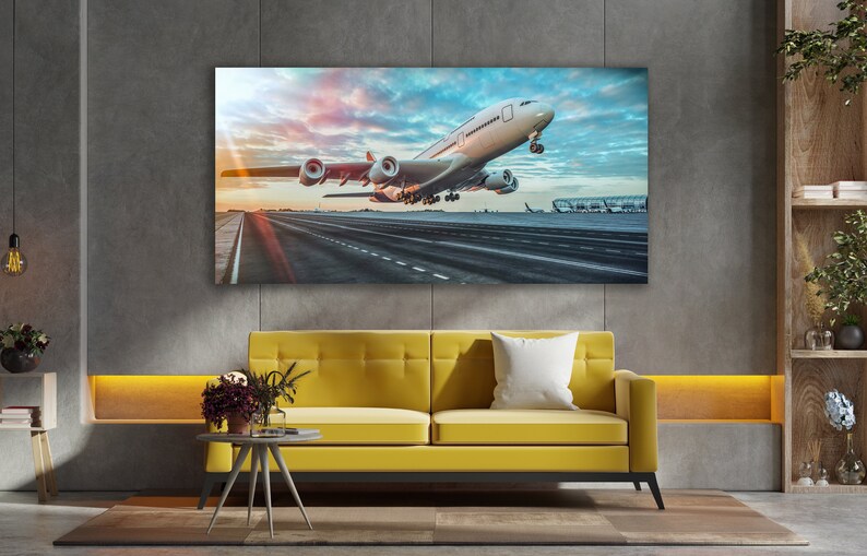 May include: A white airplane taking off from a runway at an airport. The airplane is in the foreground of the image, and the runway is in the background. The sky is blue and cloudy, and the sun is shining.