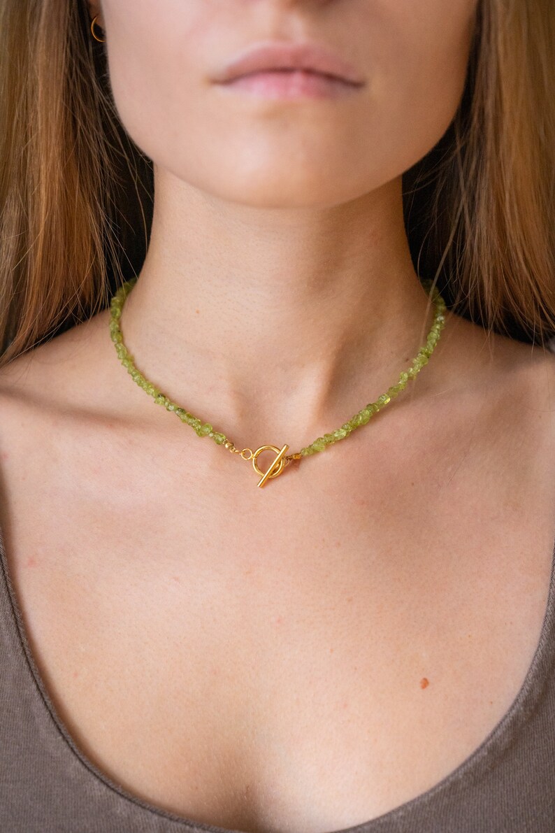 Green peridot choker necklace with small gemstones and a golden toggle closure