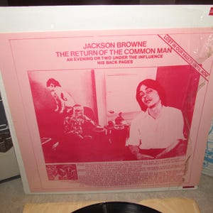 May include: A vintage vinyl record album cover featuring a pink and red design. The album is titled "The Return of the Common Man" by Jackson Browne. The cover art includes a portrait of a man and other illustrations.