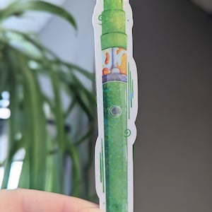 May include: A green and iridescent vape pen sticker with a white background. The sticker has a cartoon-style design and features a green and white vape pen with a white cloud of smoke coming out of the top.
