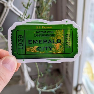 May include: A green and gold sticker with a ticket design. It says "B.S. Express. Admit one. Destination: Emerald City. 1939 1939".