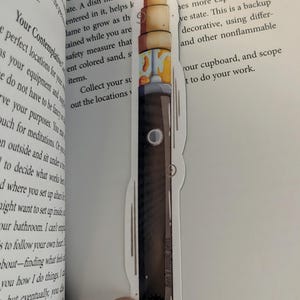 May include: A sticker featuring a stylized illustration of a vape pen. The pen has a dark brown body with a light brown top and colorful accents. The text "Ben's magic pens" is printed on the sticker.