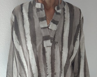 May include: A long-sleeved, loose-fitting shirt with a V-neck and a striped pattern in shades of brown and white.