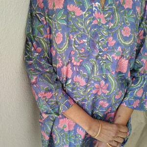 May include: A blue and pink floral print tunic top with a V-neck and three-quarter sleeves.