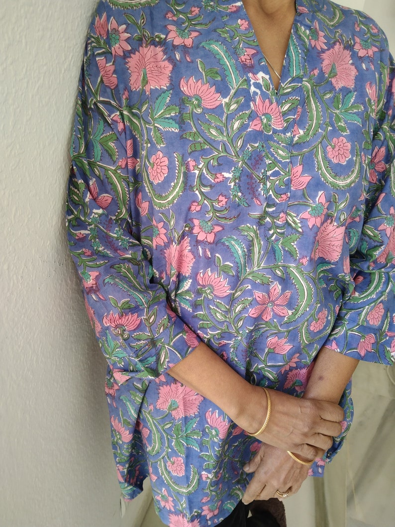 May include: A blue and pink floral print tunic top with a V-neck and three-quarter sleeves.