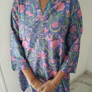 May include: A blue and pink floral print tunic top with a V-neck and three-quarter sleeves.