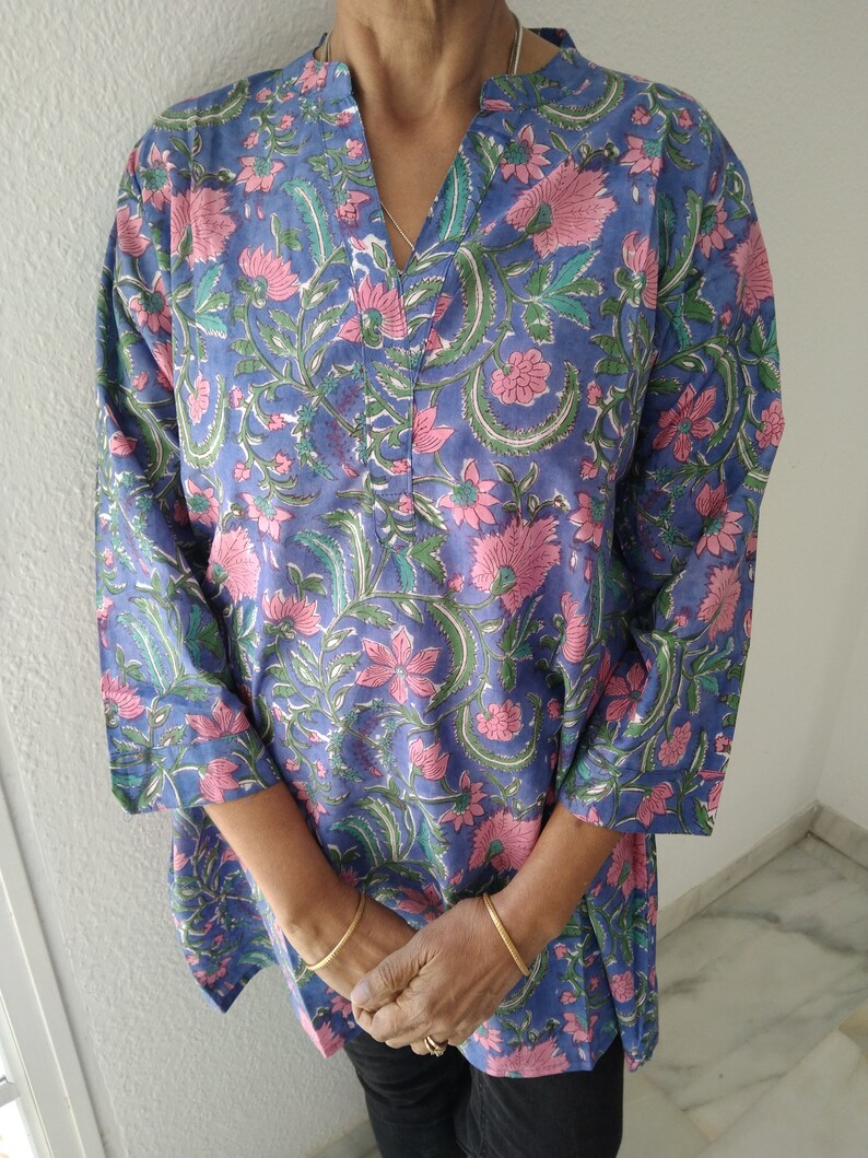 May include: A blue and pink floral print tunic top with a V-neck and three-quarter sleeves.