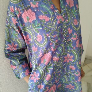 May include: A long-sleeved, blue cotton shirt with a pink and green floral print. The shirt has a V-neck and a relaxed fit.