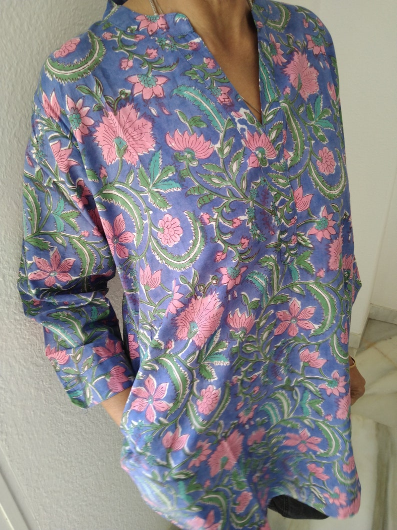 May include: A long-sleeved, blue cotton shirt with a pink and green floral print. The shirt has a V-neck and a relaxed fit.
