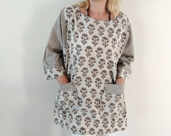 May include: A beige and brown cotton tunic with a floral print and two patch pockets. The tunic has a relaxed fit and a slightly longer length.