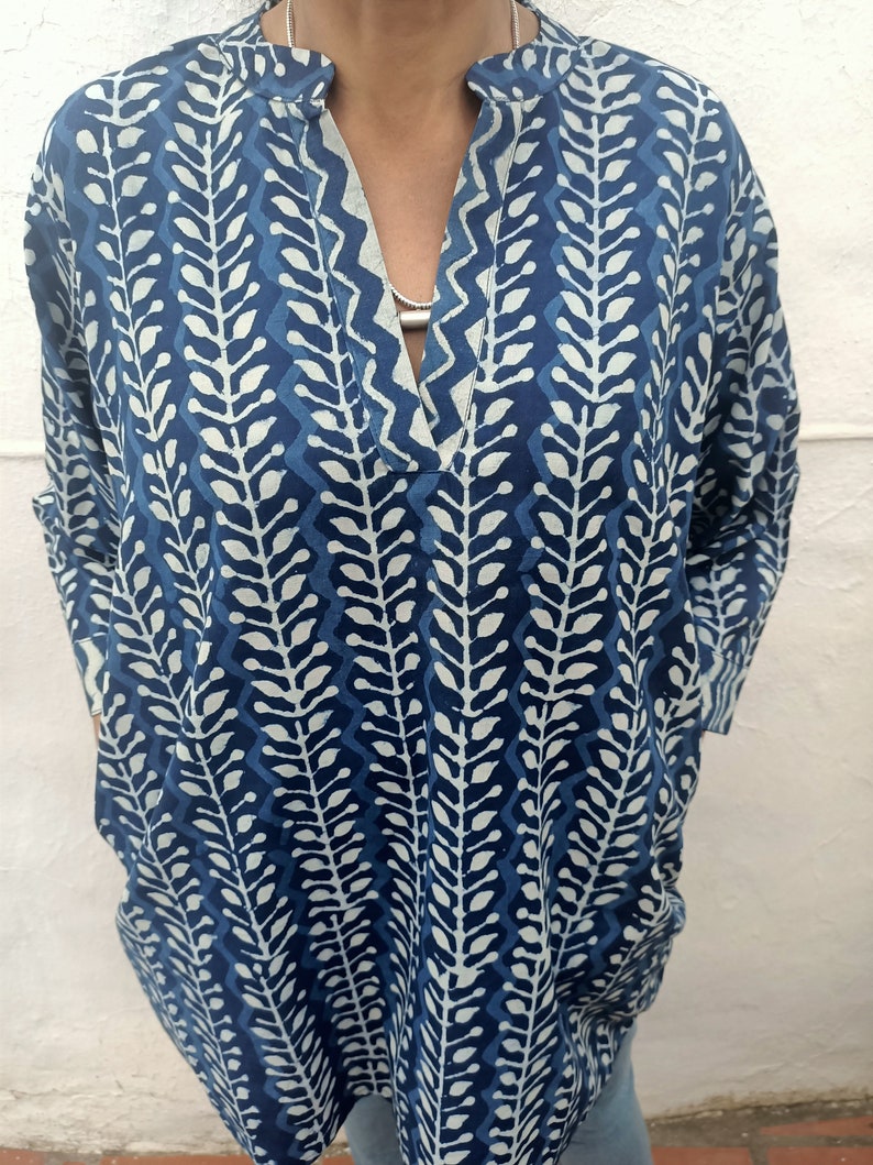 Op de afbeelding: Een blauwe en witte gepatroneerde tuniek met een V-hals en lange mouwen.