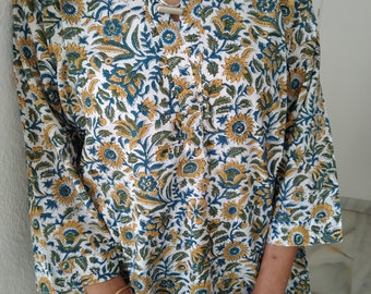 May include: A white tunic with a floral print in shades of blue, yellow, and green. The tunic has a mandarin collar and long sleeves.