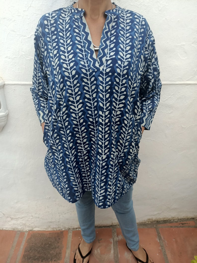 Op de afbeelding: Een blauwe tuniek met een wit patroon, een V-hals en lange mouwen. De tuniek heeft een losse pasvorm en is gemaakt van een lichtgewicht stof.