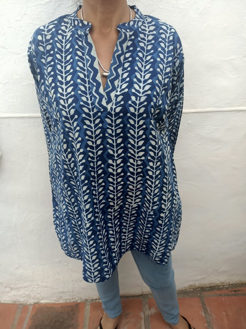 Op de afbeelding: Een tuniek met lange mouwen met een blauw en wit bladmotief. De tuniek heeft een V-hals en een losse pasvorm.
