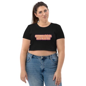 May include: A black cropped t-shirt with short sleeves and the text "someone fall in love with me" in a retro, colorful font.