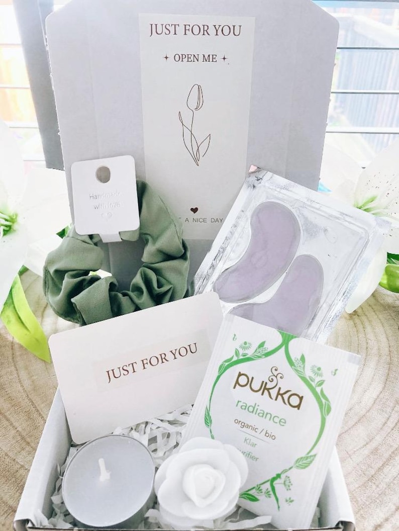 May include: A gift box containing a green scrunchie, eye patches, a tea bag, a white candle, and a decorative flower. The box includes a card that says "JUST FOR YOU" and a card that says "Hairpin with love". The box also has a card that says "JUST FOR YOU" and "+ OPEN ME +".