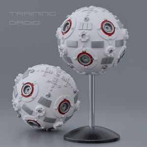 Op de afbeelding: Twee witte bolvormige droids met rode en grijze accenten. Eén droid staat op een standaard, de andere op een vlakke ondergrond. De tekst "TRAINING DROID" staat boven de droids.
