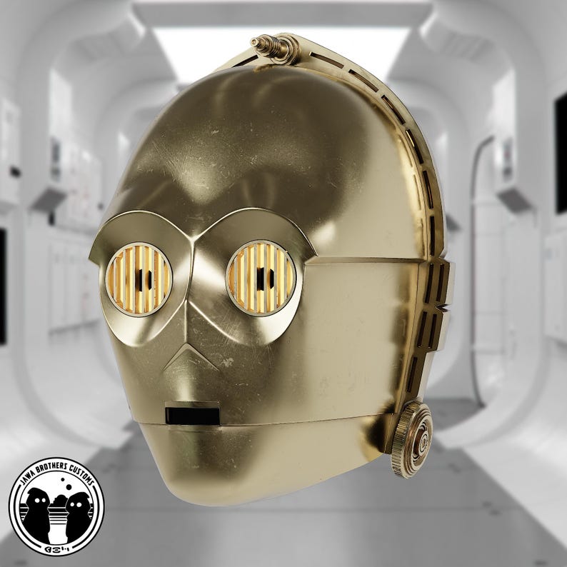 May include: A golden-colored C-3PO head replica, featuring detailed mechanical elements. The eyes have a grid-like pattern, and the head has a smooth, metallic finish. The Jawa Brothers Customs logo is visible at the bottom left.