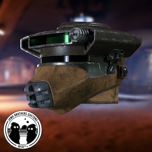 May include: A weathered, brown and green helmet with a visor and a small, round, black and silver antenna on top. The helmet has a textured surface and appears to be made of metal and leather. The helmet is a prop from the Star Wars universe.