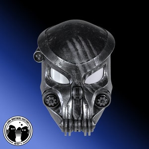 Könnte beinhalten: Ein schwarzer und silberner Helm mit einer verwitterten, metallischen Oberfläche. Der Helm hat ein Visier und ein detailliertes Design mit einer strukturierten Oberfläche.