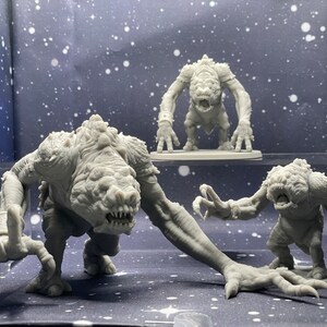 May include: Three gray, detailed, plastic figurines of creatures with sharp teeth and claws. The creatures are posed in a menacing stance.